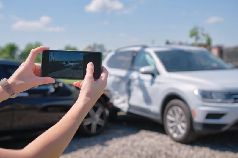 Person taking a photo of a car accident scene with their phone.