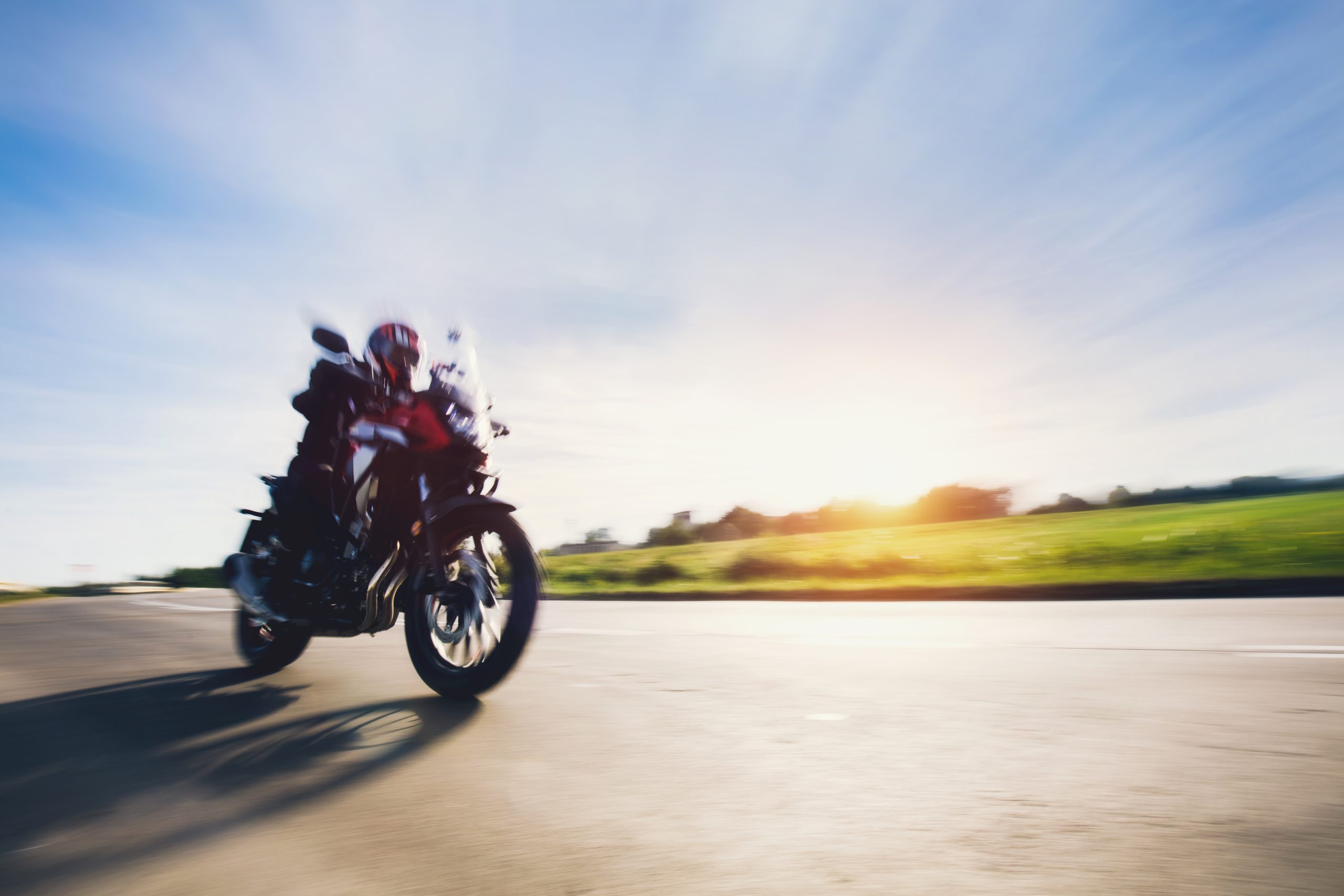 Rider on motorcycle in motion on asphalt road.