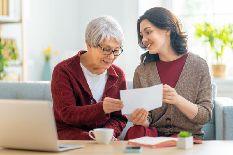 Smiling older woman and younger woman reviewing a document together.