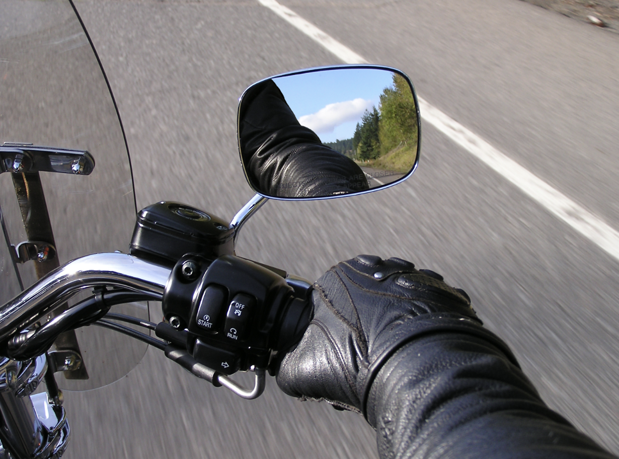 Motorcyclist gripping the throttle with a mirror view of the scenery