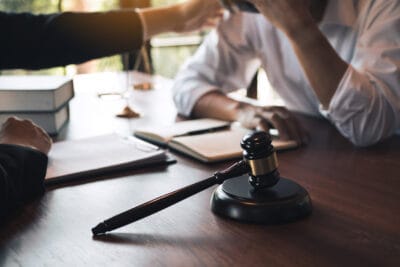 Lawyer consoling a stressed client at a desk with legal documents and a gavel in focus.